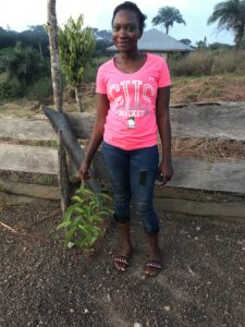 Jennifer Jabbie, Jusu's daughter proudly shows off a healthy young tree